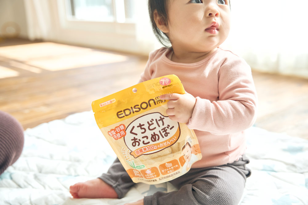 くちどけおこめぼーの袋を持つ赤ちゃん