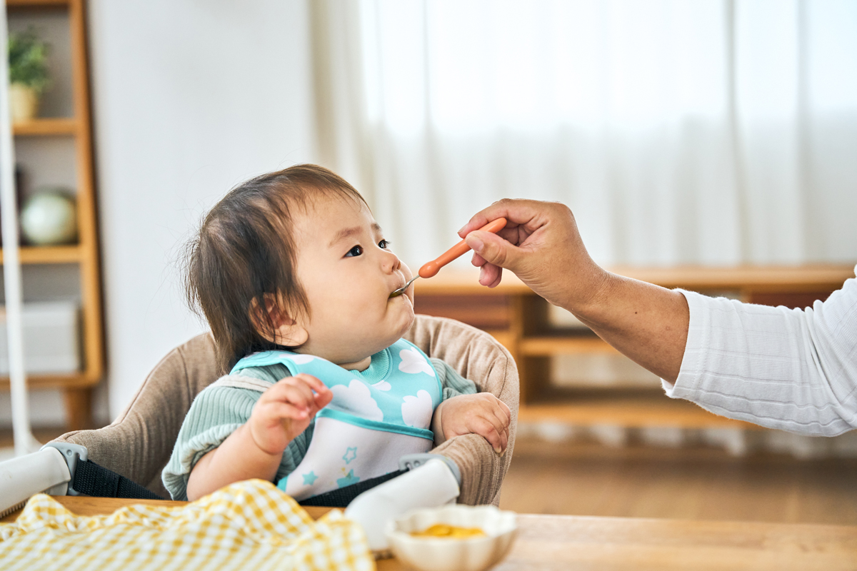 食物アレルギーの現状：お母さんに離乳食を食べさせてもらっている赤ちゃん