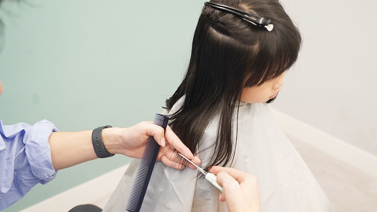エジモットの子ども散髪はさみを使って髪の毛を逃がさずに真っ直ぐカットするプロの手元