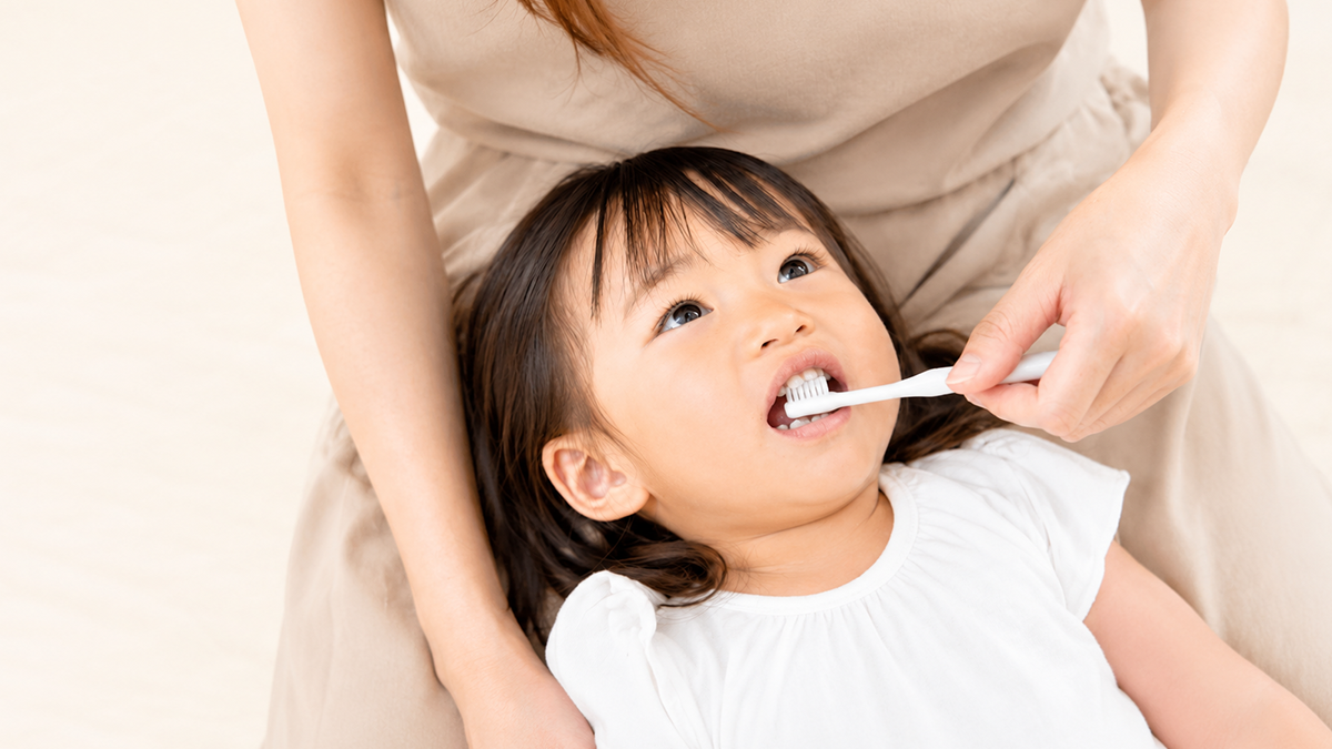 歯磨きを嫌がる子どもと寄り添う親